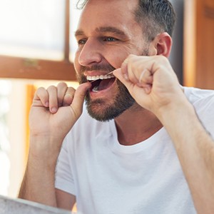 Patient in Raleigh flossing their dental implants