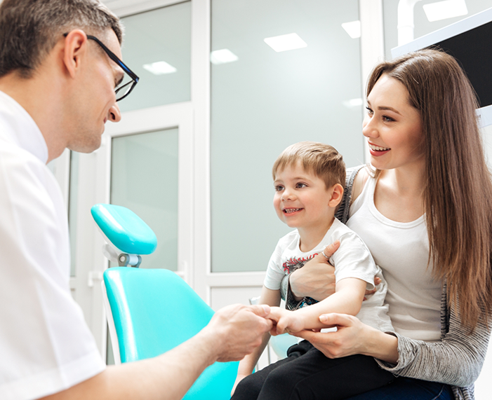 Young woman with her toddler in her lap talking to dentist in Raleigh