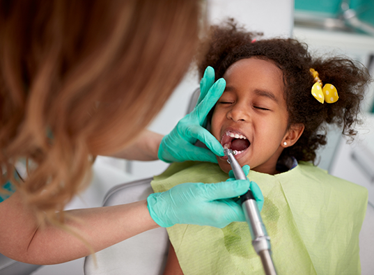 Young girl in dental chair receiving a teeth cleaning