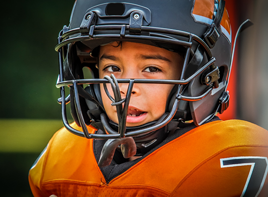 Child wearing a football helmet and uniform