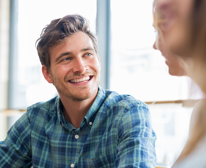 Man in blue and green plaid shirt smiling with dental implants in Raleigh