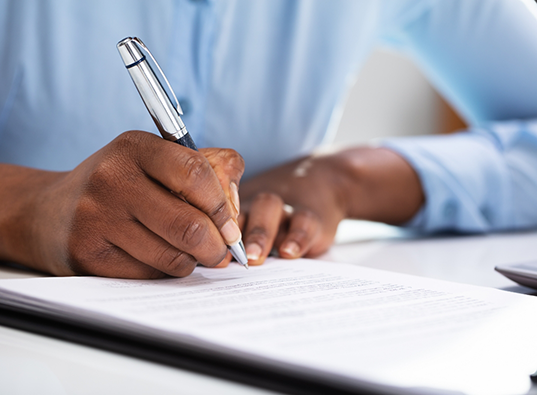 Person filling out paperwork on a clipboard