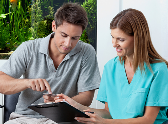 Dental team member showing a patient where to sign on a clipboard