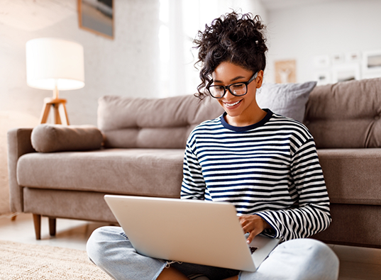 Woman sitting on floor and typing on laptop