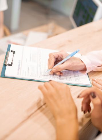 Dental team member showing a patient where to sign on paperwork