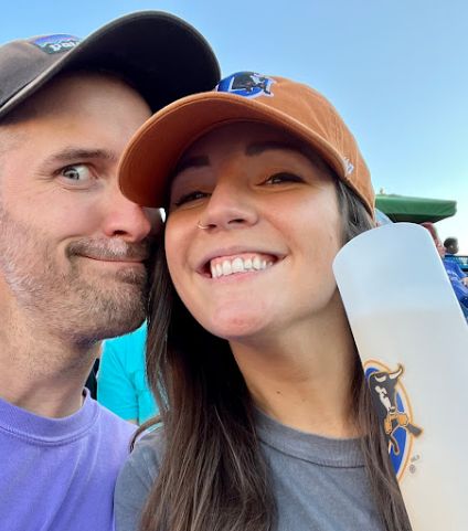 Young woman taking selfie with young man outdoors while holding plastic water bottle