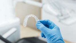 Gloved hand holding an Invisalign clear aligner