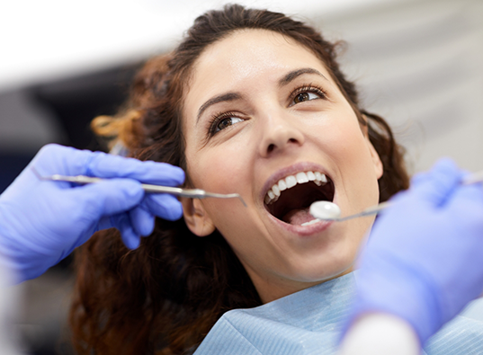 Woman looking at her dentist while receiving a dental exam