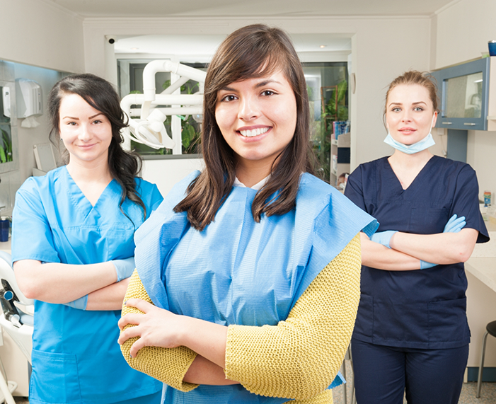 Three dental team members smiling with their arms crossed