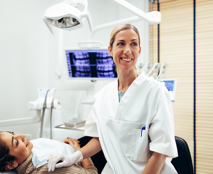 Dentist smiling in treatment room after providing a patient with dental services in Raleigh