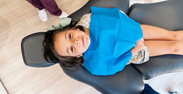 Young girl in dental chair looking up toward the camera