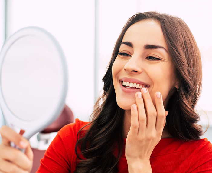 Dental patient admiring her smile after getting veneers in Raleigh